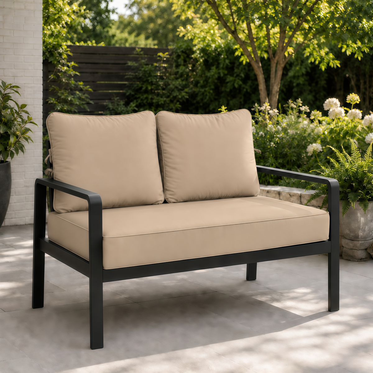 Beige outdoor loveseat cushions on a modern black metal frame set on a patio.