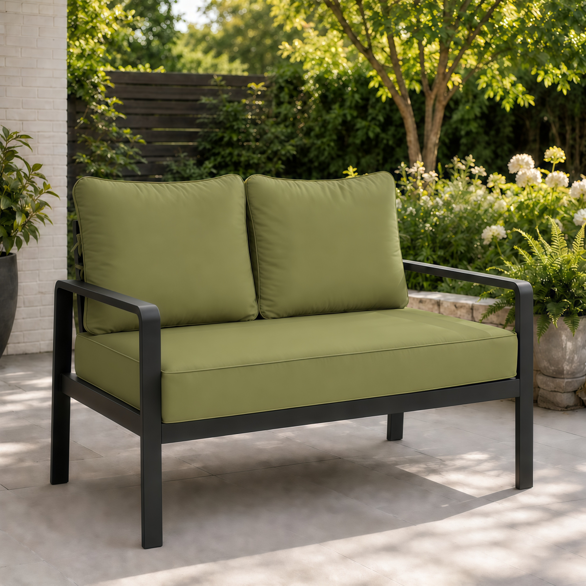 Sage green outdoor loveseat cushions on a modern black metal frame set on a patio.
