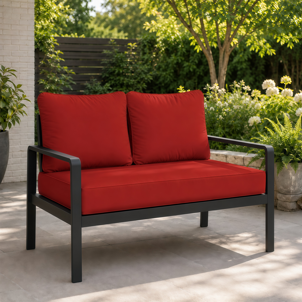 Plush red outdoor loveseat cushions on a modern black metal frame set on a patio.