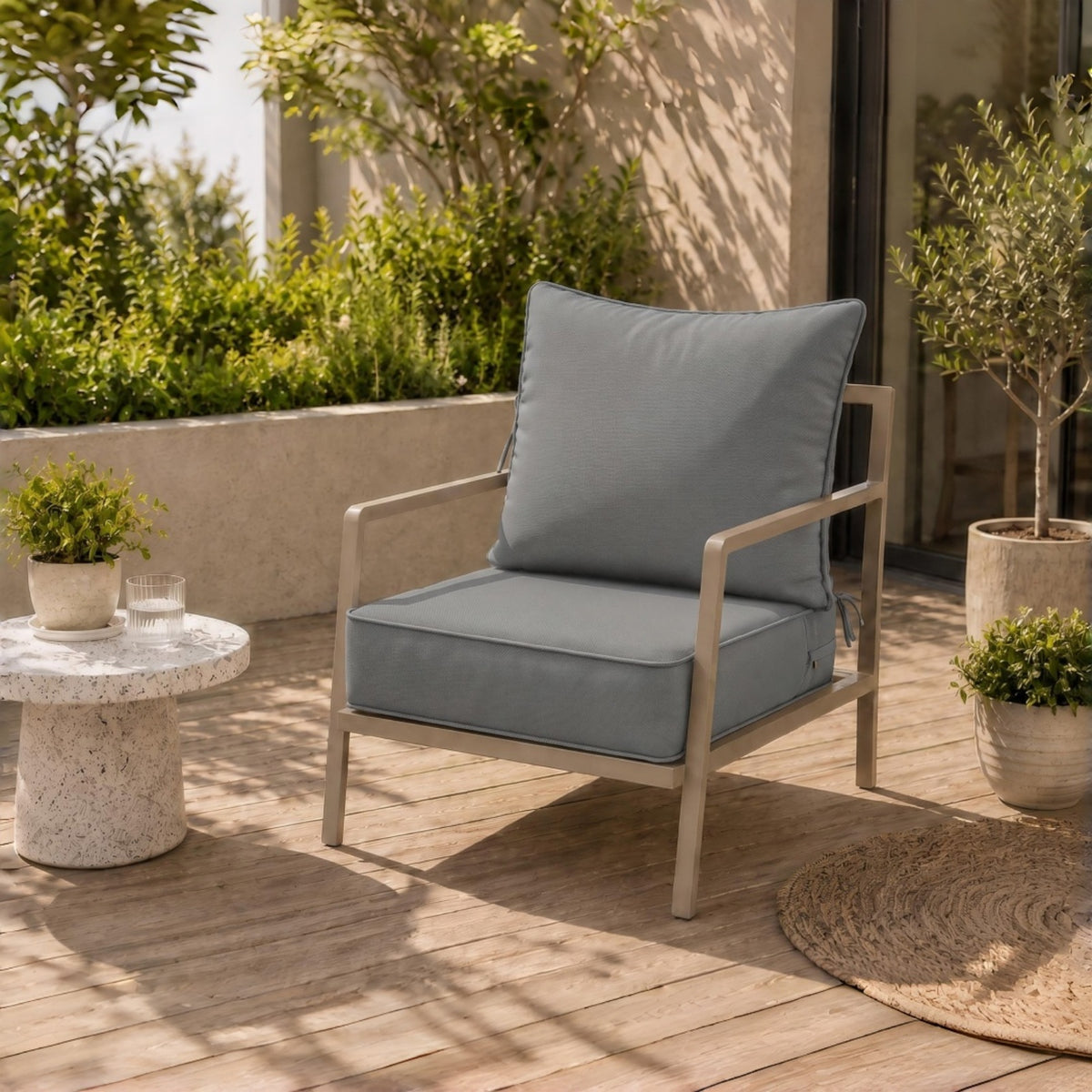 Plush grey water-resistant patio chair cushion with secure ties on a modern metal outdoor chair.