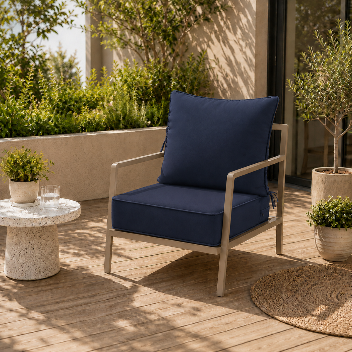 Plush navy blue outdoor chair cushion with secure ties on a modern patio chair set on a wooden deck.