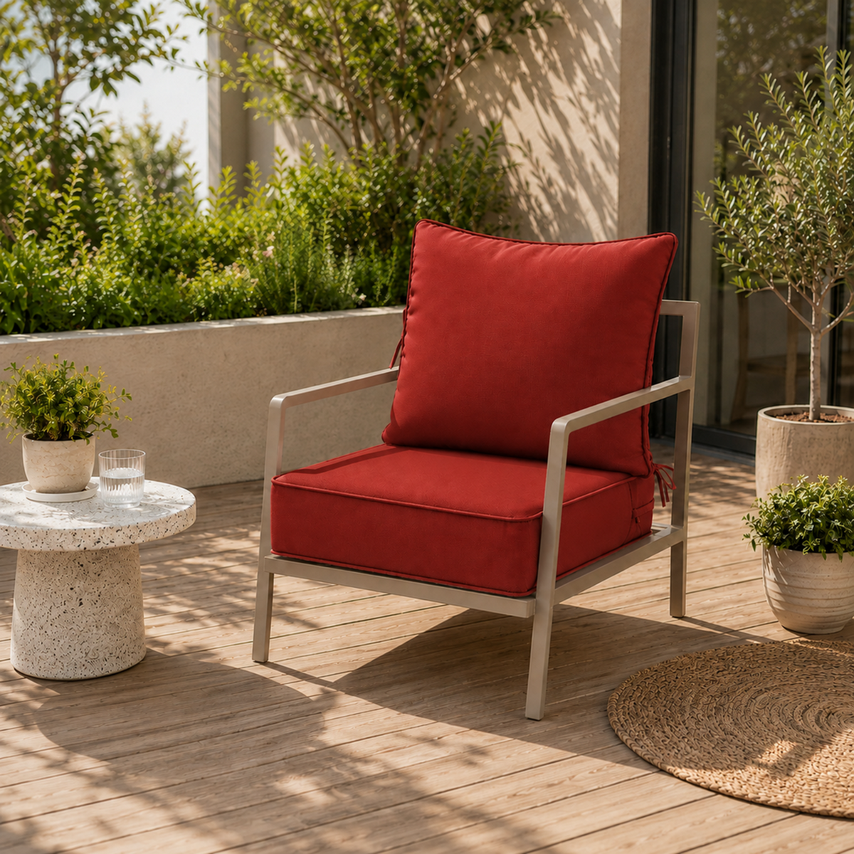 Plush red outdoor chair cushion with secure ties on a modern patio chair set on a wooden deck.