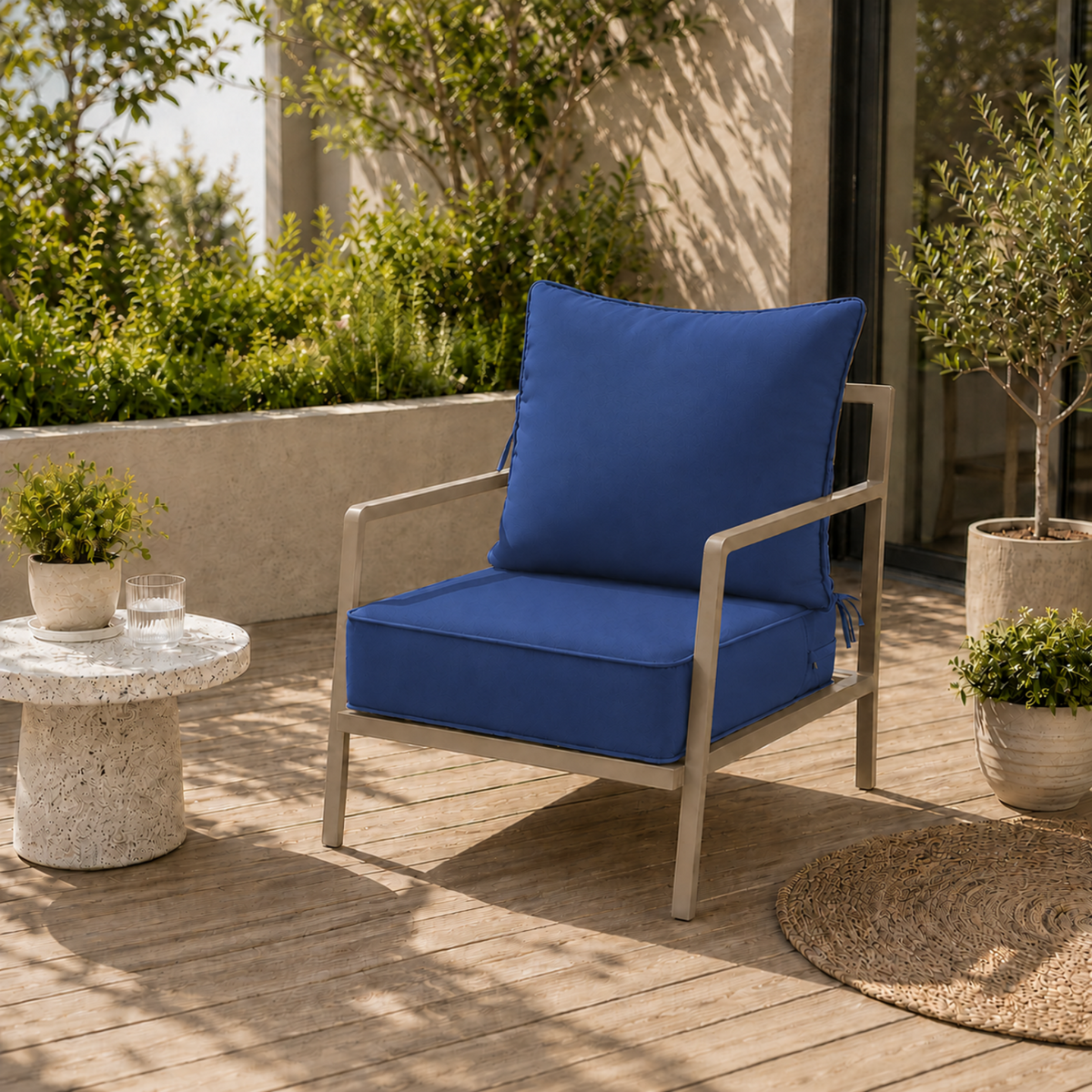 Plush royal blue outdoor chair cushion with secure ties on a modern metal patio chair on a wooden deck.