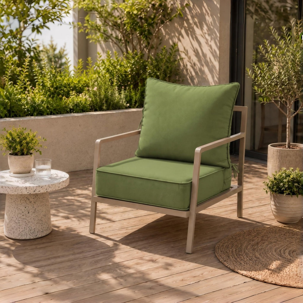 Sage green water-resistant patio chair cushion with secure ties on a modern outdoor metal chair on a sunny wooden deck.