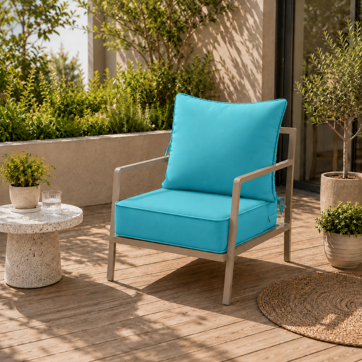 Bright turquoise water-resistant patio chair cushion with secure ties on a modern metal outdoor chair on a wooden deck.
